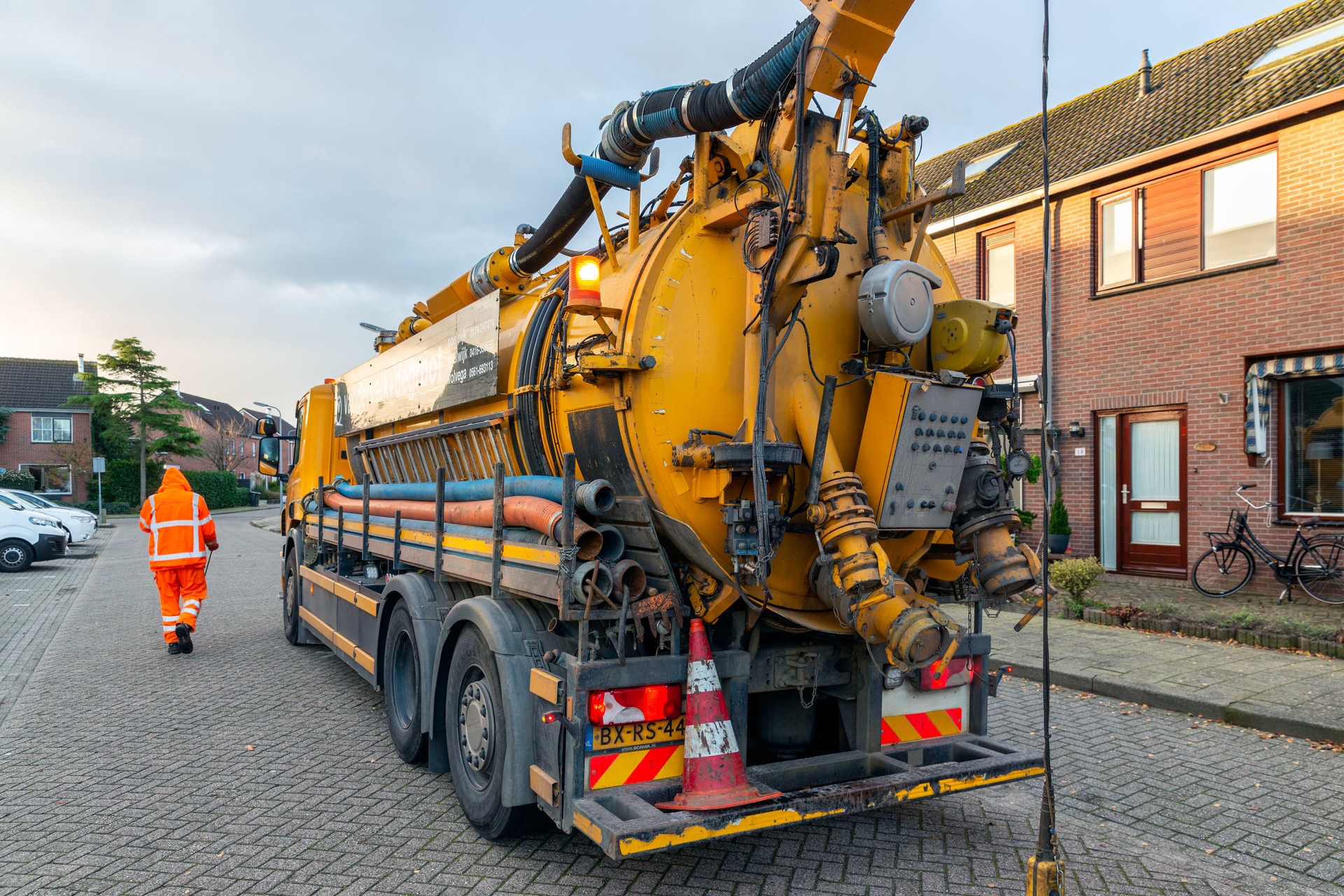 Workers with specialized truck cleaning sewer system in residential area